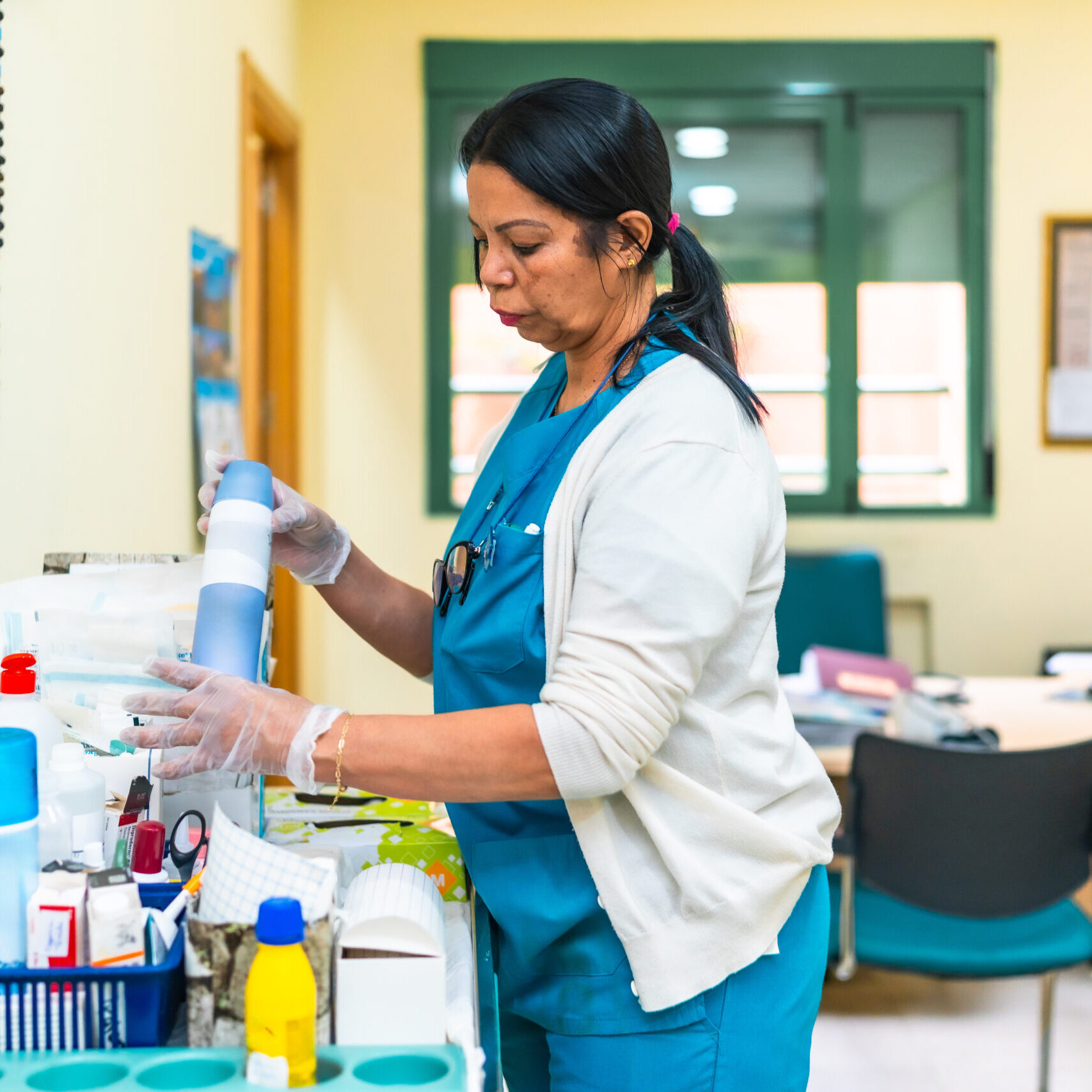Nurse wearing gloves and preparing medical equipment on a cart in a nursing home, ensuring safety and cleanliness for elderly patients